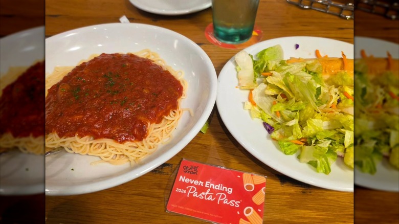 Spaghetti with sauce, salad, and an Olive Garden Pasta Pass on table