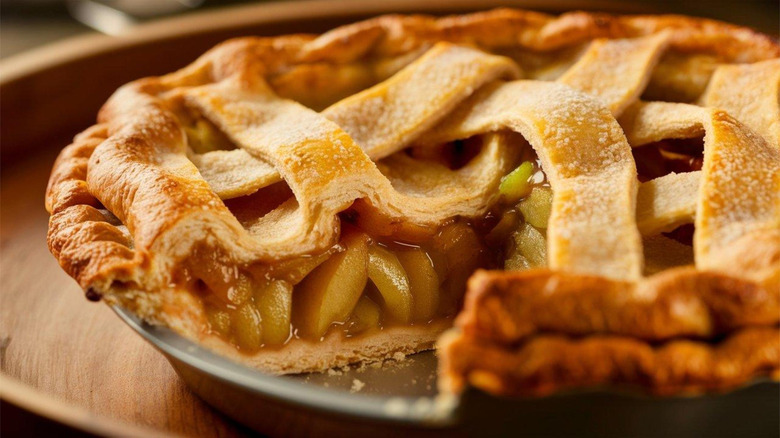 Classic apple pie with crisscross crust in pan with one slice taken out
