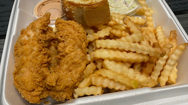 Chicken fingers, fries, garlic bread, coleslaw, and Raising Cane's sauce in a styrofoam container