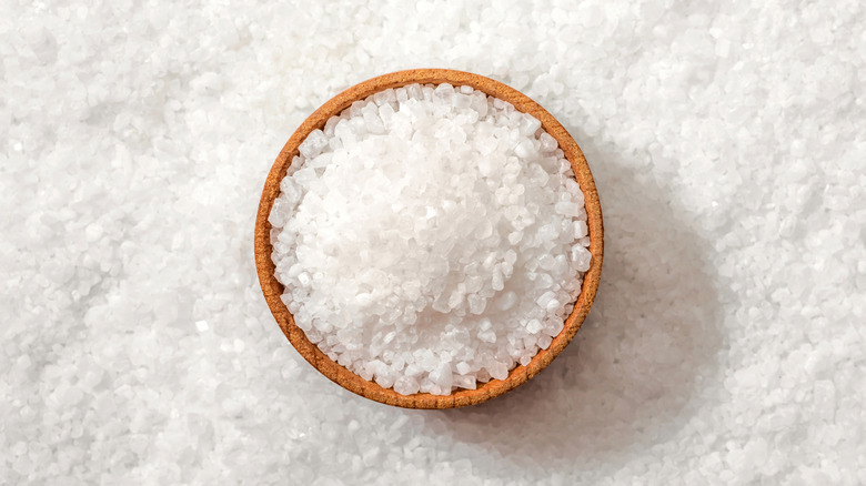 Bowl of coarse sea salt above more sea salt