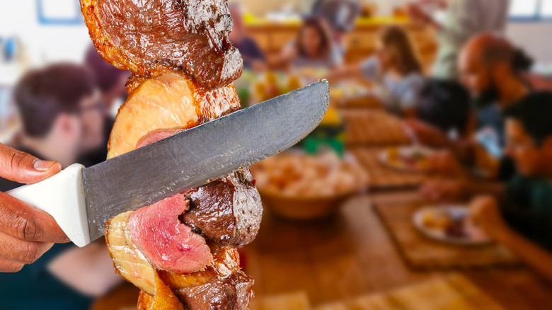 Waiter slicing beef from skewer