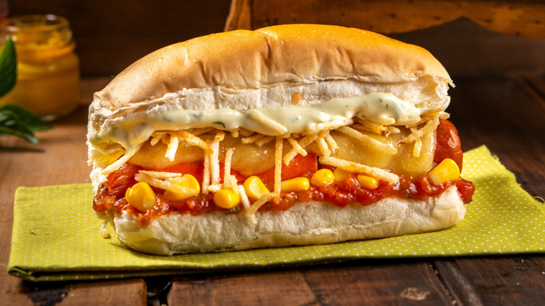 Brazilian hot dog topped with potato sticks, corn, and sauces