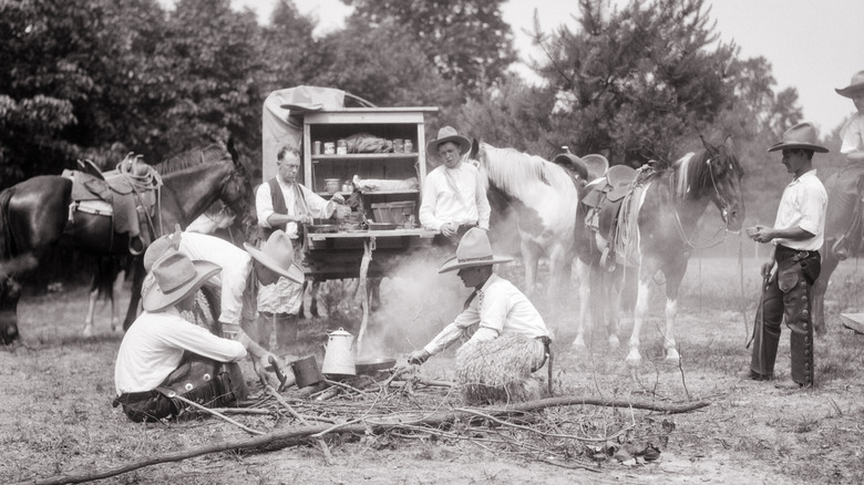 Black and white photo of cowboys cooking around chuckwagon