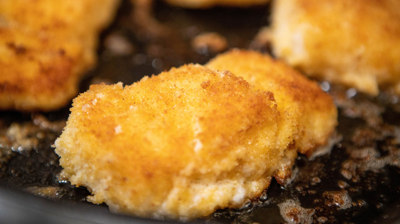 Golden brown breaded cod filets in pan