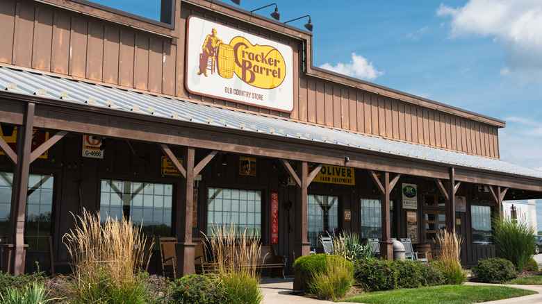 front porch entrance of cracker barrel with restaurant sign above wooden awning