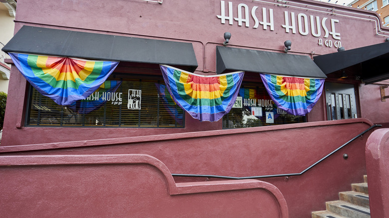 exterior of hash house a go go with stairs leading up to entrance decorated with rainbow flags
