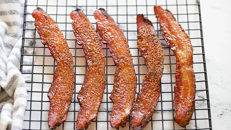Five strips of crisp candied bacon on a rack