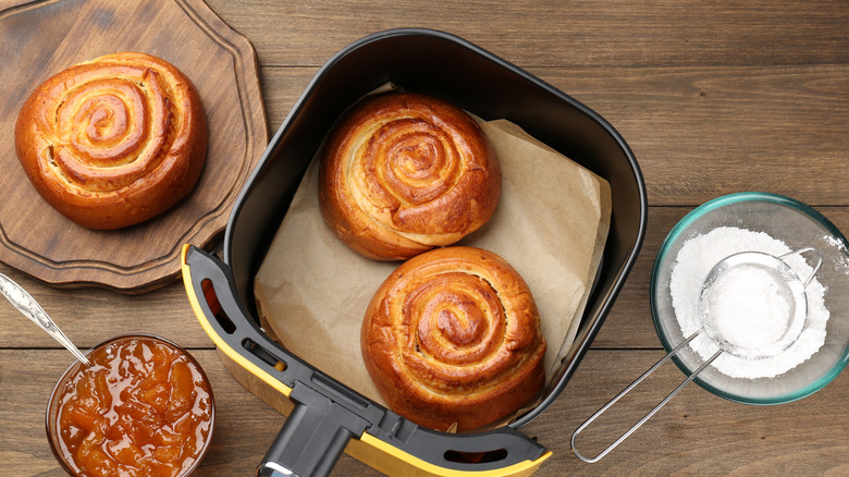 Cinnamon rolls inside and next to an air fryer