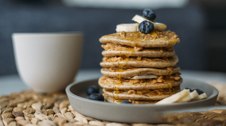 A stack of homemade pancakes with blueberries and banana on a plate