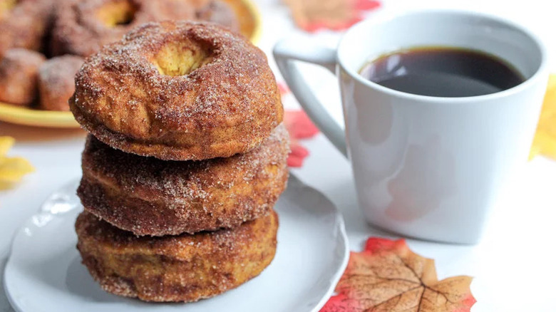 A stack of pumpkin spice donuts with a cup of coffee