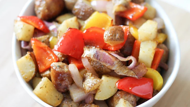A bowl of sausage and potatoes with onions and bell peppers