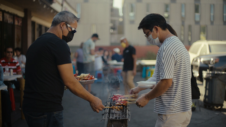 Two people roasting meat on stick