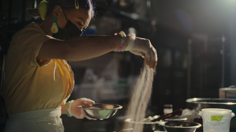 A woman sprinkling and holding a bowl