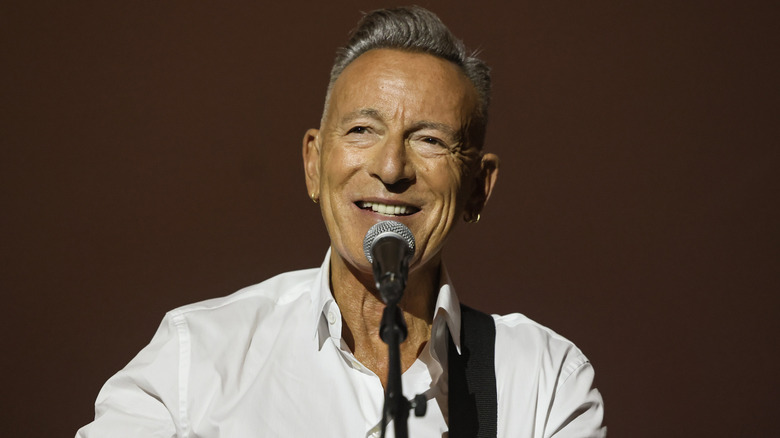 Bruce Springsteen smiling behind microphone.