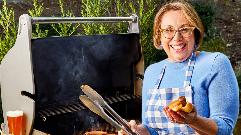 Babs holding hot dog next to grill