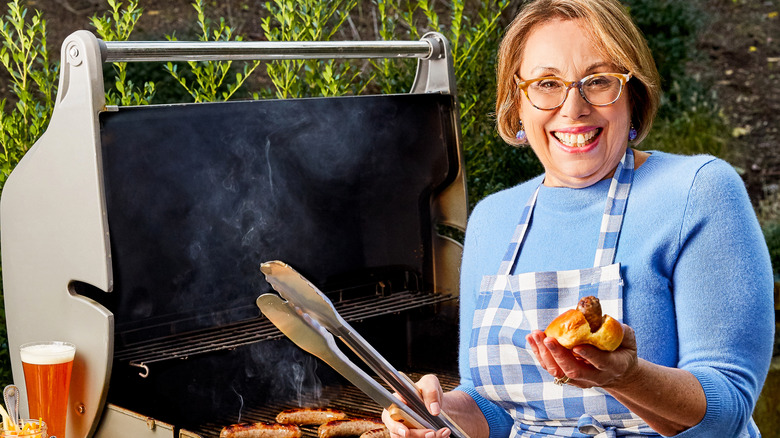 Babs holding hot dog next to grill