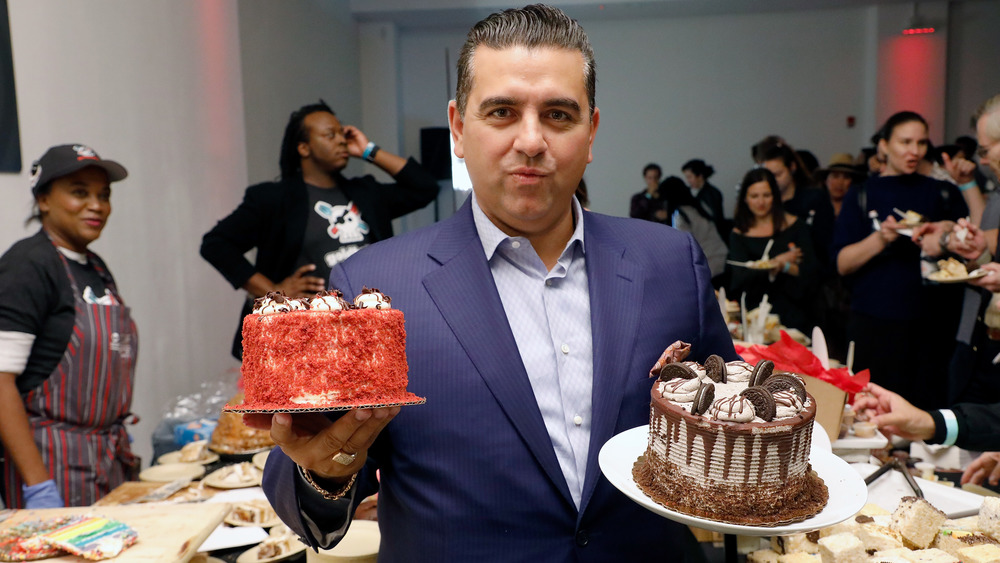 Buddy Valastro holding up two cakes