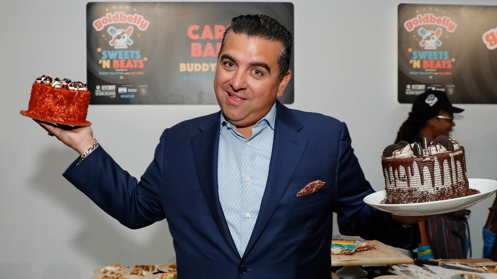 Buddy Valastro holding up two cakes