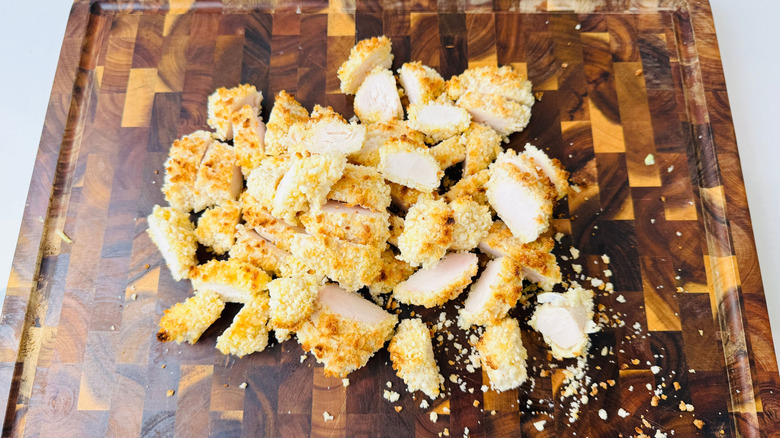 Sliced breaded chicken on wooden board
