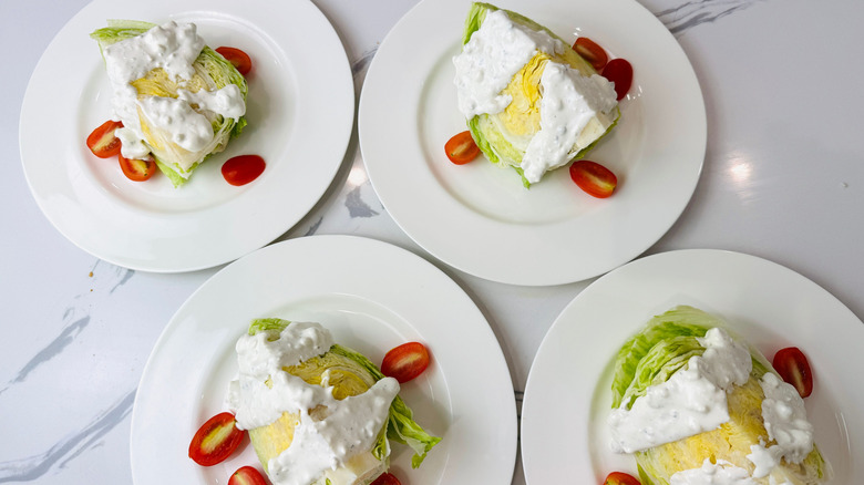 Wedge salads on plates with dressing and cherry tomatoes