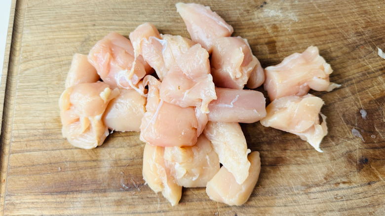 Sliced raw chicken on wooden board