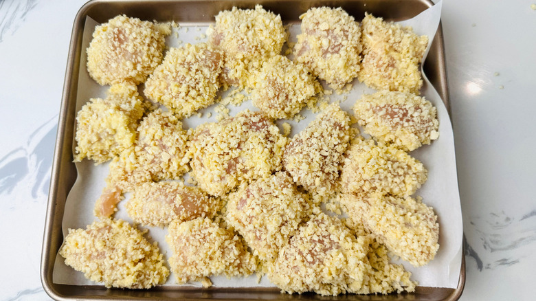 Breadcrumb coated chicken pieces on baking sheet