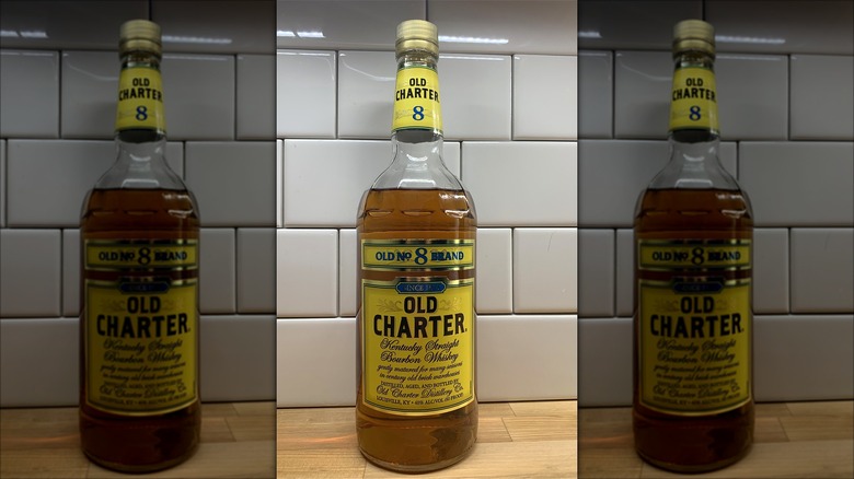 A bottle of Old Charter 8 bourbon against a white tile wall.