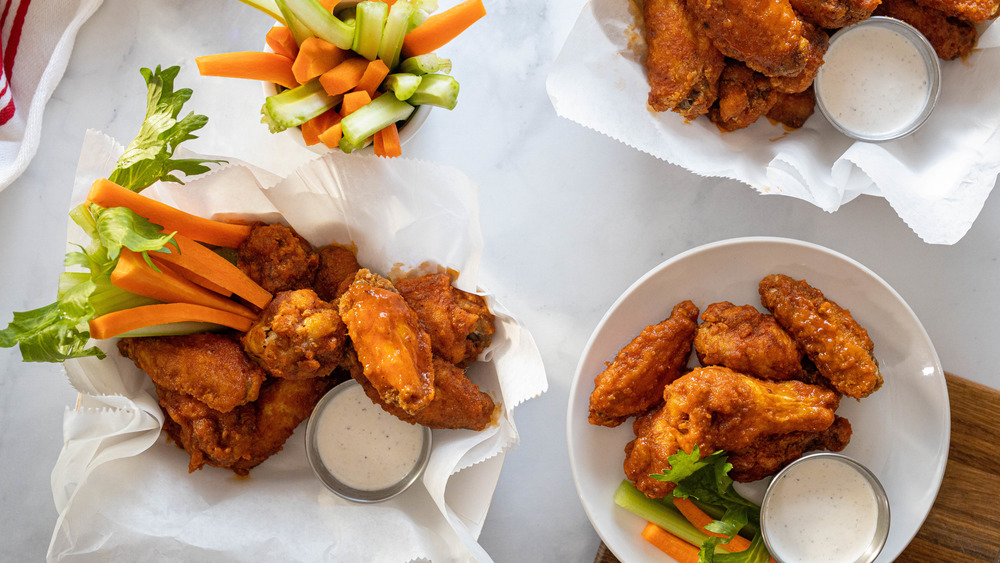 buffalo wings on white surface with celery and carrots