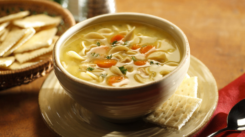 Bowl of chicken noodle soup with crackers