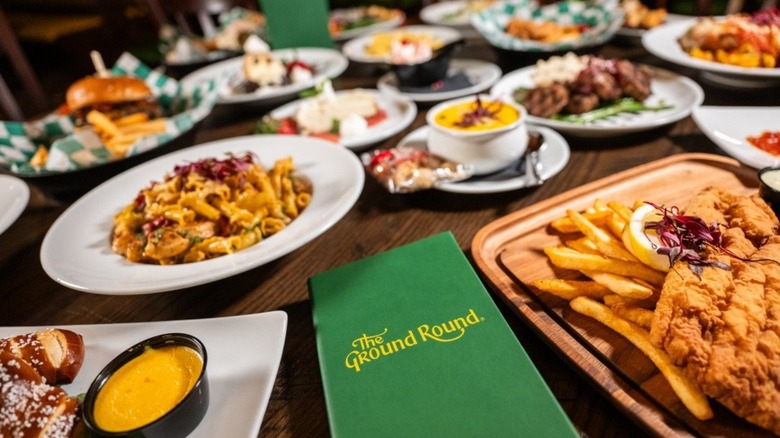 Assorted menu items on restaurant table arranged around green Ground Round menu.
