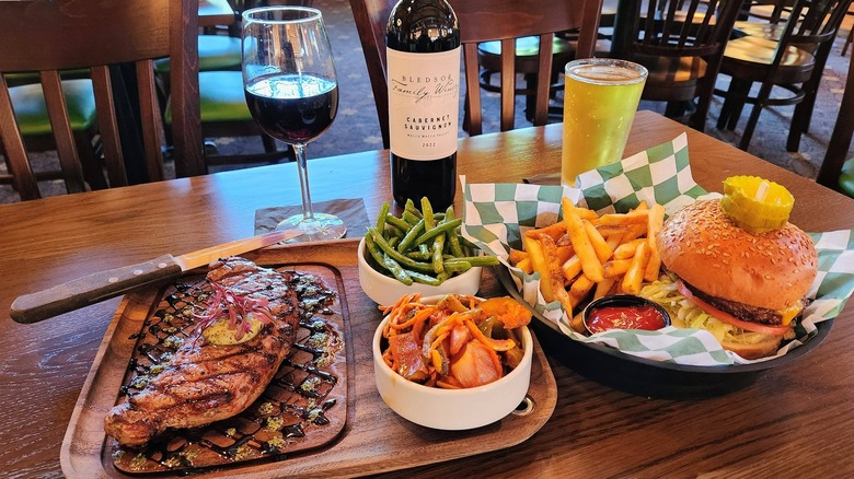 Grilled salmon and cheeseburger with sides and drinks on restaurant table.