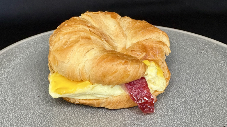 Bacon, egg, and cheese croissant sandwich on gray plate