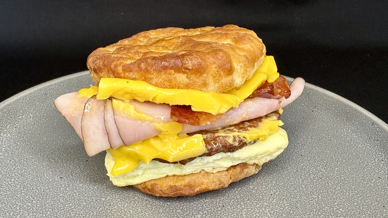 Ham, bacon, sausage, egg, and cheese biscuit sandwich on gray plate