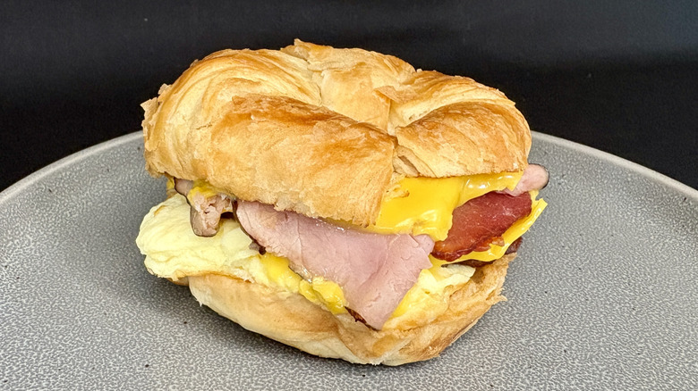 Ham, bacon, sausage, egg, and cheese croissant sandwich on gray plate