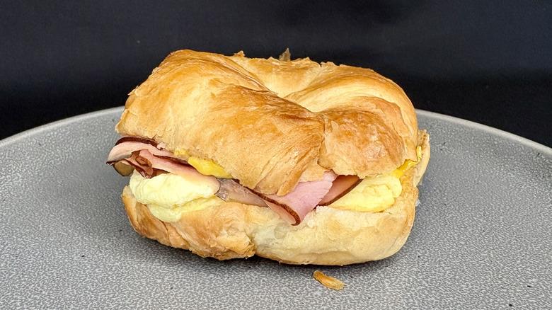 Ham, egg, and cheese croissant sandwich on gray plate