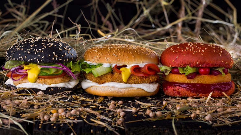 Three burgers on a pile of straw