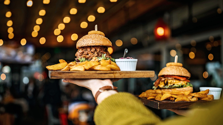 Server carrying two burgers in restaurant