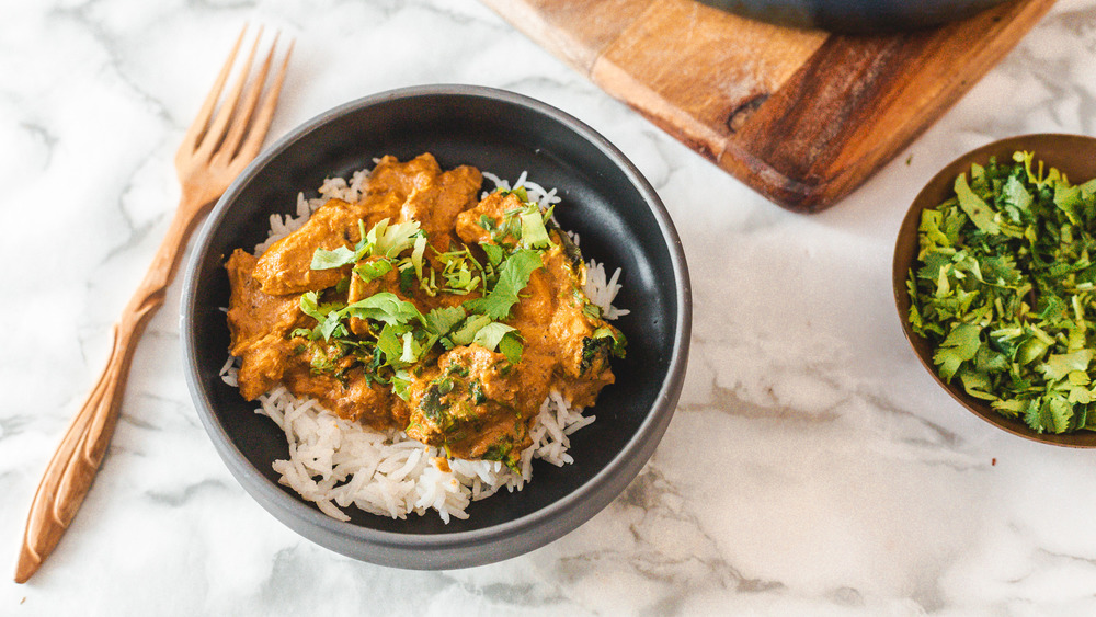 bowl of butter chicken next to cilantro