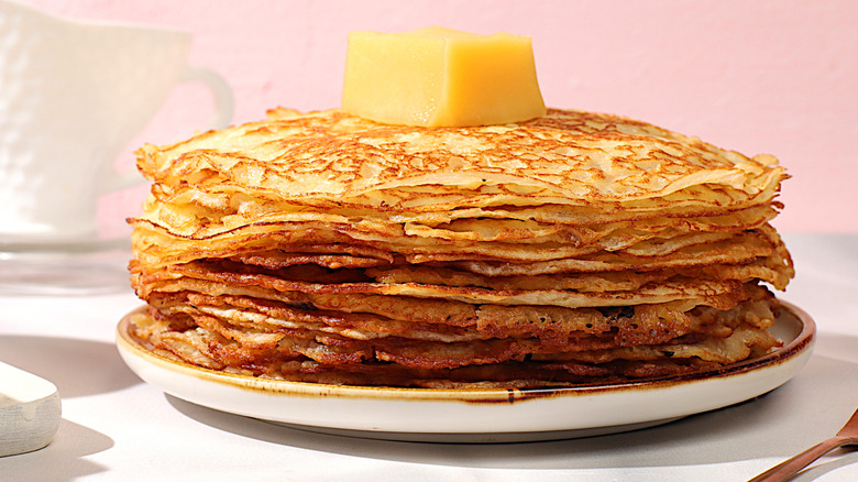 A stack of crispy pancakes with a pat of butter on top