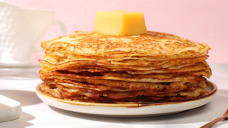 A stack of crispy pancakes with a pat of butter on top