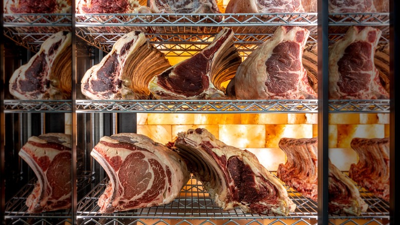 Dry-aged steaks sitting on metal racks