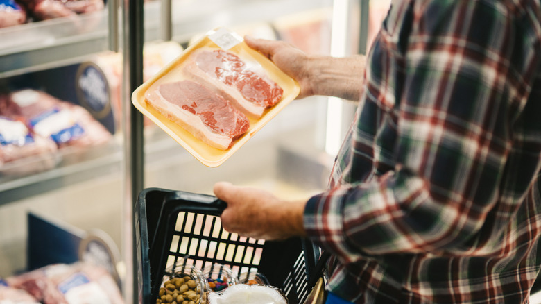 Person looking at frozen package of meat in grocery store