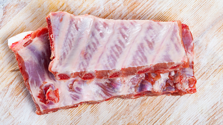 The underside of a rack of pork ribs showing the membrane