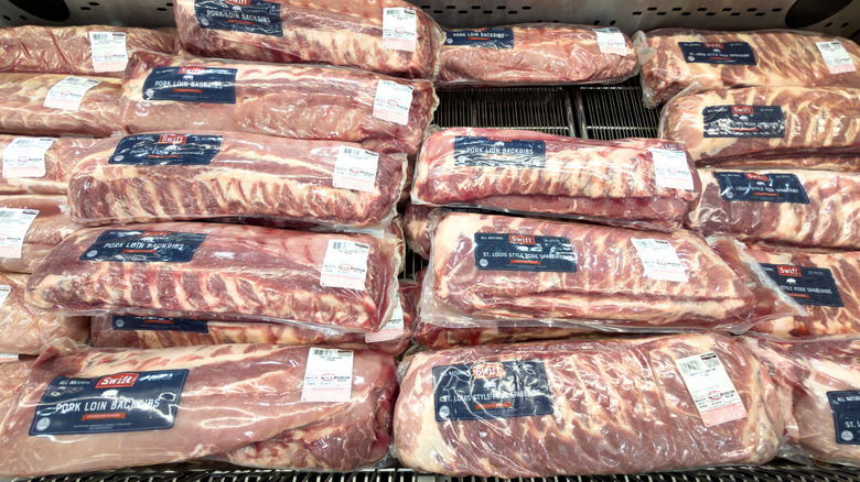 Multiple packages of pork ribs on display inside a supermarket