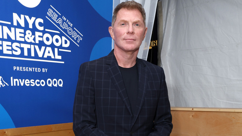 Bobby Flay in a blue jacket at a publicity event.
