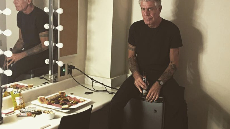 Anthony Bourdain sitting beside mirror
