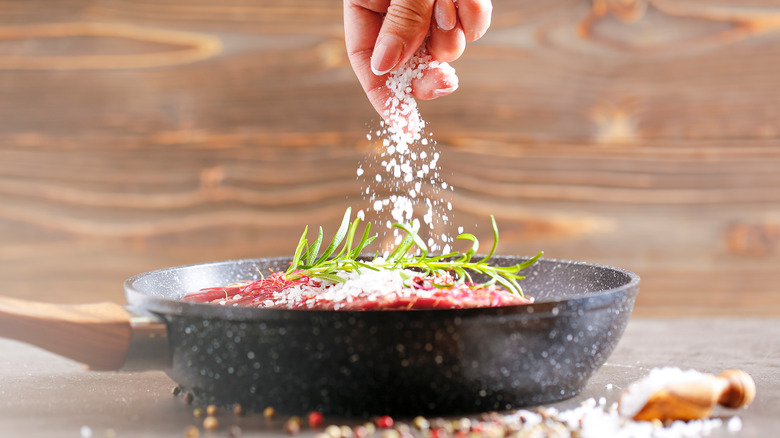 salt onto steak in skillet