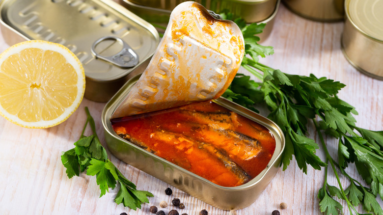 Open can of sardines on wooden table