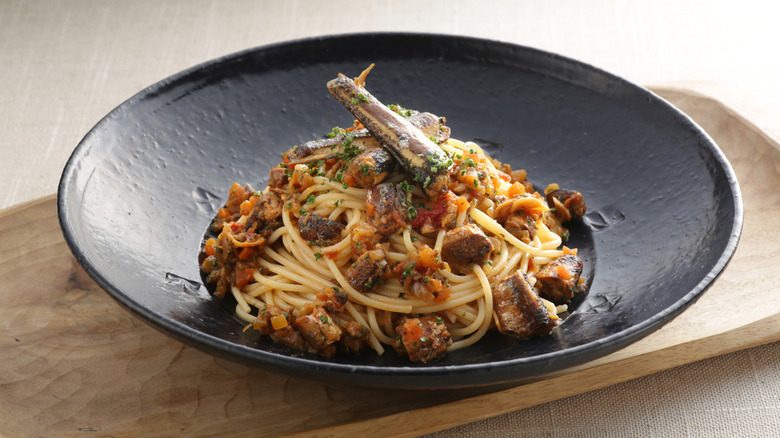 Black bowl of seafood pasta with sardines