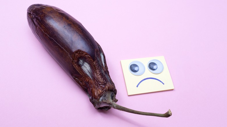 Spoiled brown eggplant next to a frowny face post-it note